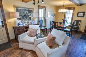 A cozy living room with a fireplace, a dining area, and a kitchen in the background. - Historic Elk Ave 3 Master Suites + Hot Tub - Walk Everywhere (Crested Butte)
