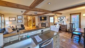 A spacious kitchen with a stone backsplash, wooden beams, and a large island with a sink and dishwasher. - Historic Elk Ave 3 Master Suites + Hot Tub - Walk Everywhere (Crested Butte)