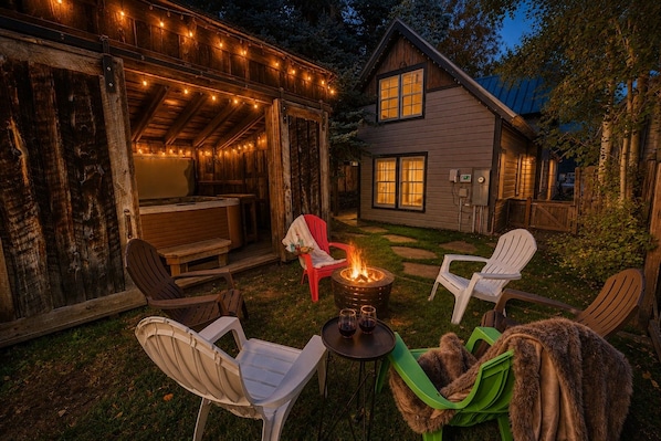 A cozy outdoor seating area with a fire pit, wooden chairs, and a dining table.