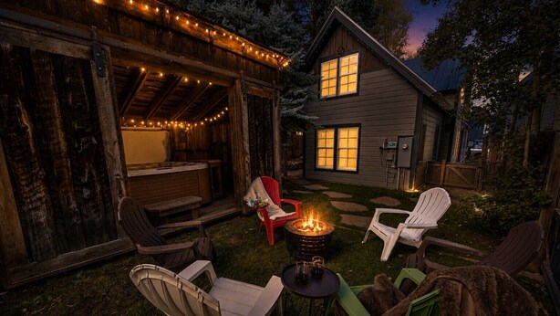 An outdoor seating area with chairs, a fire pit, and string lights. - Historic Elk Ave 3 Master Suites + Hot Tub - Walk Everywhere (Crested Butte)