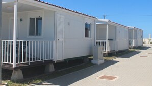 A row of white mobile homes with balconies, numbered B5, along a paved street.