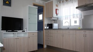 A modern kitchen with wooden cabinets, a built-in microwave, and a flat-screen TV.