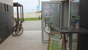 Ein Verleihkiosk mit einem Schild, das die verfügbaren Artikel wie Roller, Fahrräder und Campingausrüstung auflistet.