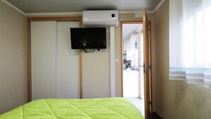Ein Hotelzimmer mit Bett, Wandfernseher und einer Tür zu einem Korridor.