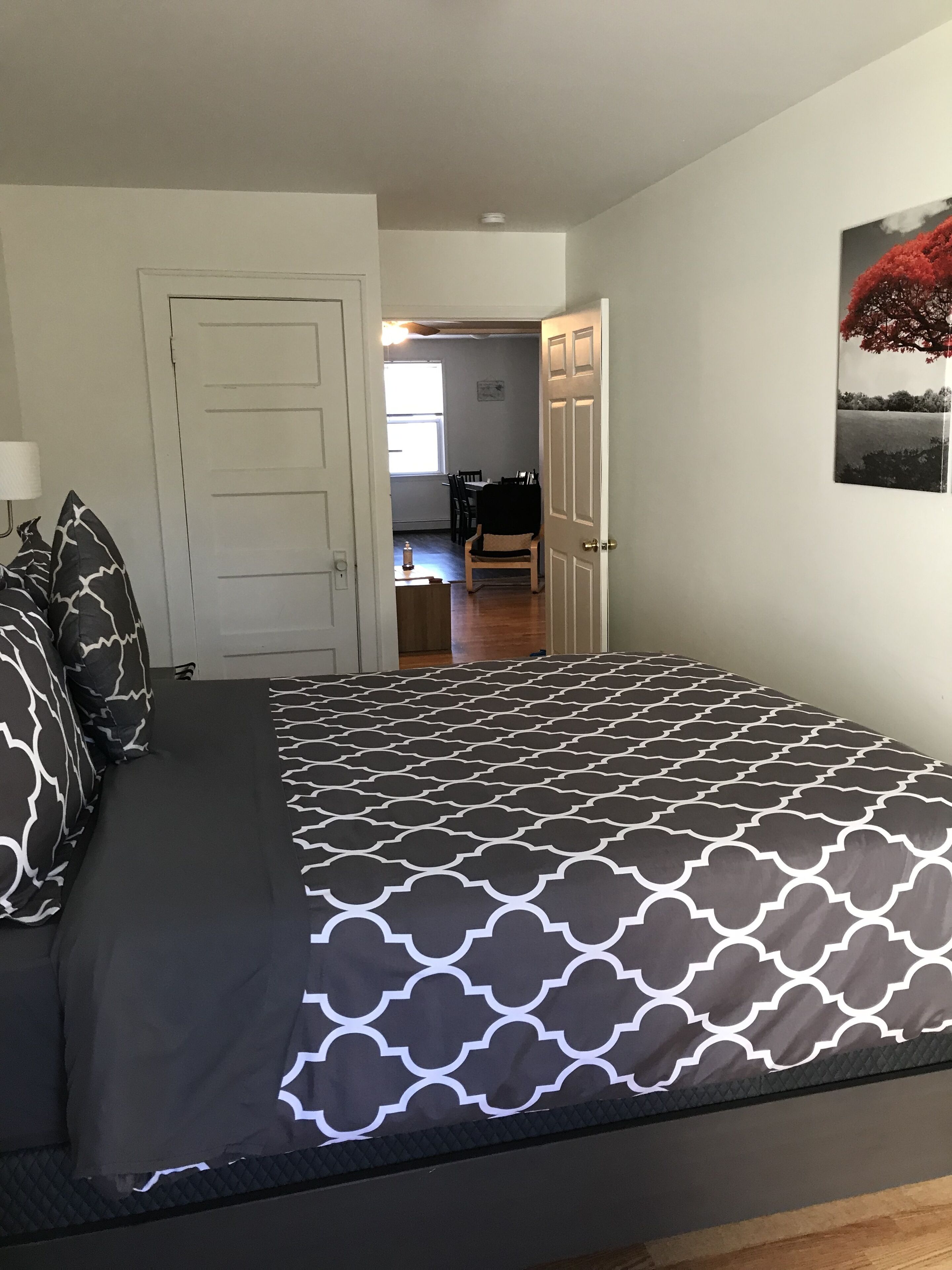 A bedroom with a bed, pillows, a door, and a wall with a picture.