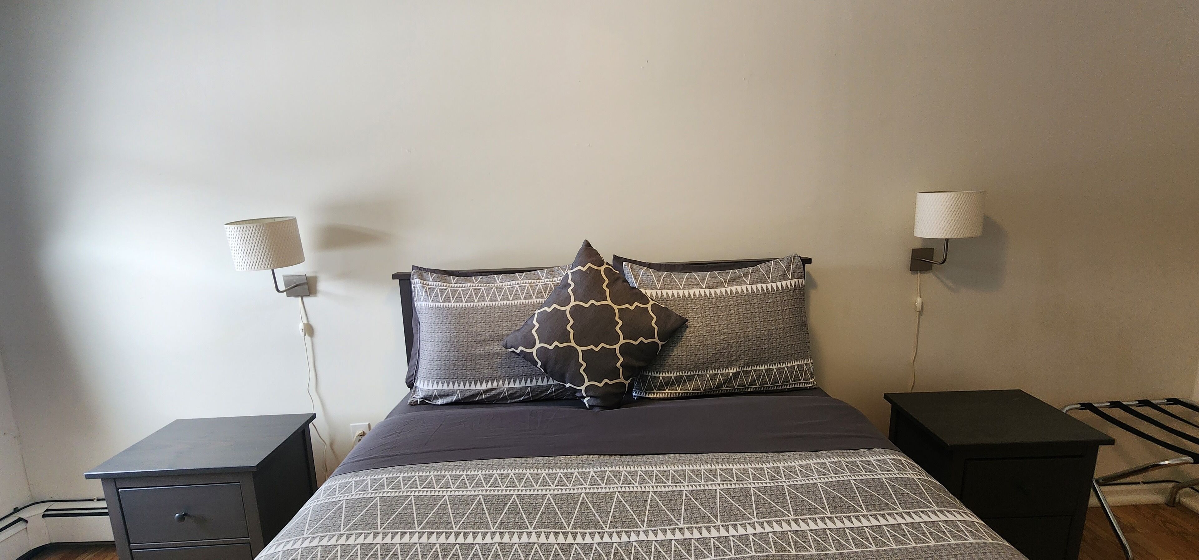A neatly made bed with patterned bedding and two bedside lamps.