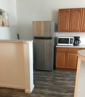 A kitchen with wooden cabinets, a stainless steel refrigerator, a microwave, and a coffee maker.