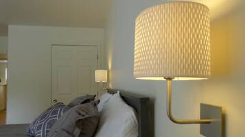A bedroom with a bed, a wall-mounted lamp, and a door in the background.