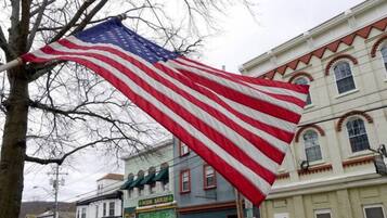 Et amerikansk flag vaver foran en bygning med markise i grøn farve og et skilt med teksten "Baker's".