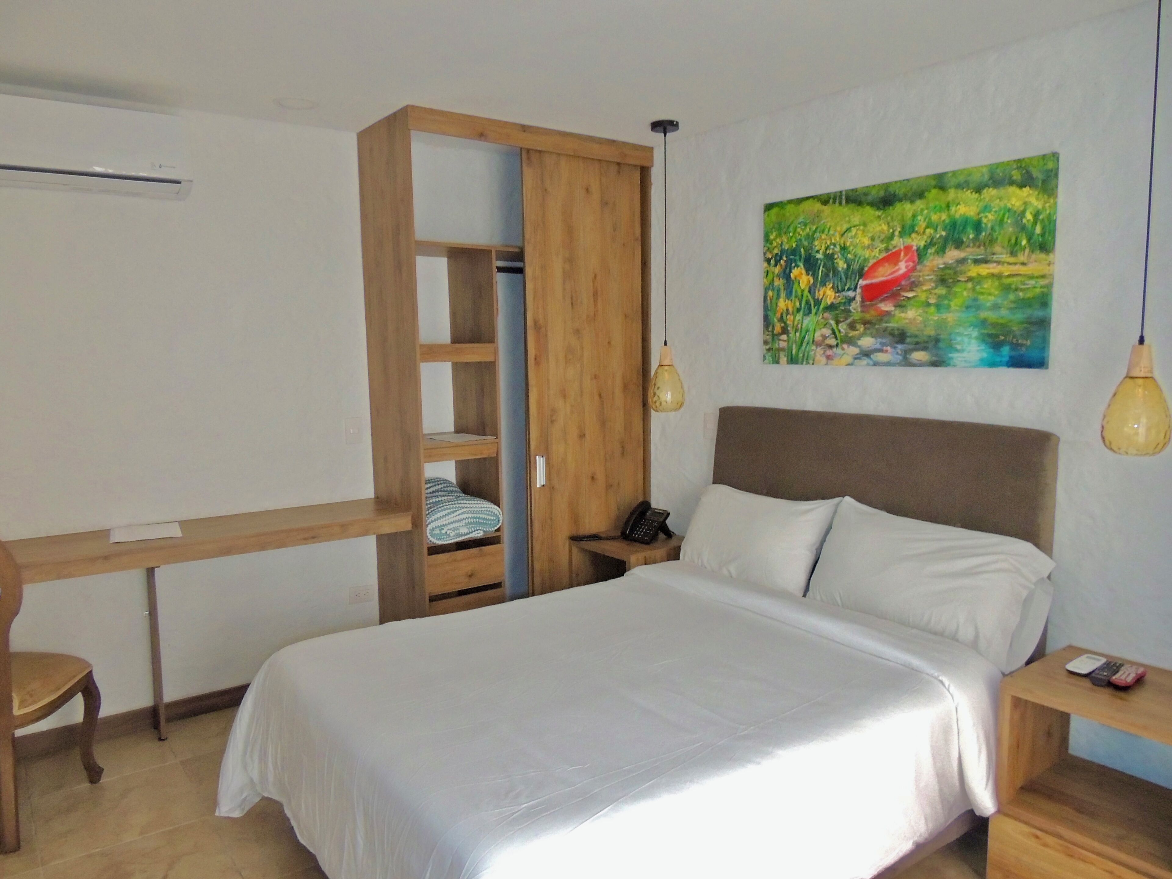 Un dormitorio con cama, un armario de madera, un escritorio y un cuadro en la pared.
