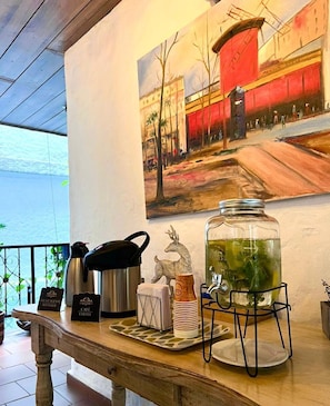 A café setup with a coffee pot, a thermos, a jar of tea, and a sign indicating hot water and coffee services. - Hotel Casa del Hidalgo Centenario - Business & Leisure (Cali)