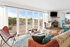 Amplia sala de estar con un ventanal, televisor y chimenea.