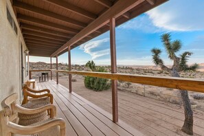 Una terraza de madera con sillas y vistas al paisaje desértico.