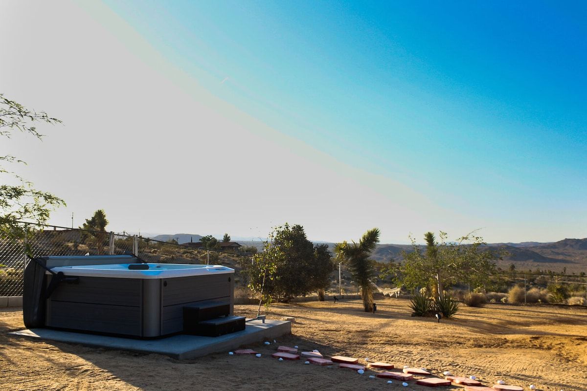 A hot tub in an outdoor setting with a clear sky and distant mountains.