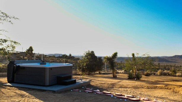 A hot tub in an outdoor setting with a clear sky and distant mountains. - High View Haven - 5min to Park, Hot Tub, Fire Pit, BBQ (Joshua Tree)