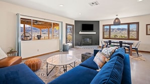 A modern living room with a fireplace, large windows, and a view of mountains.