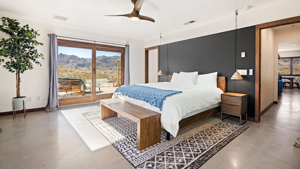 A bedroom with a large bed, a ceiling fan, a view of mountains, and a sliding glass door. - Dreamspace - Hot Tub, Fire Pit, 5 Min to Park! (Joshua Tree)