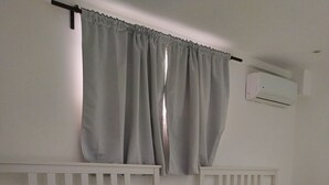 A twin room with two beds, a small bedside table, and an air conditioning unit on the wall. - Apartamento Amueblado en Santo Domingo (Santo Domingo)