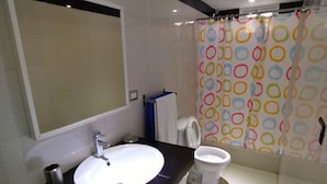 A modern bathroom with a white sink, a toilet, and a shower curtain with colorful circles. - Apartamento Amueblado en Santo Domingo (Santo Domingo)