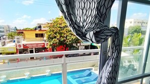 A balcony with a swimming pool, a view of the cityscape, and a building with a sign for a restaurant. - Apartamento Amueblado en Santo Domingo (Santo Domingo)
