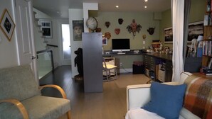 Un soggiorno con divano, poltrona, televisore e angolo cottura dotato di frigorifero, forno a microonde e utensili da cucina.