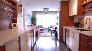 A modern kitchen with white cabinets, a central island, and a dining area with a sofa and chairs. - Junction Contemporary Home (Toronto)