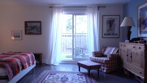 Una camera da letto con un letto, una sedia, una cassettiera e una finestra con tende.