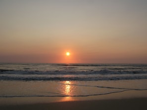 Un atardecer sobre el océano con olas que avanzan hacia la orilla.