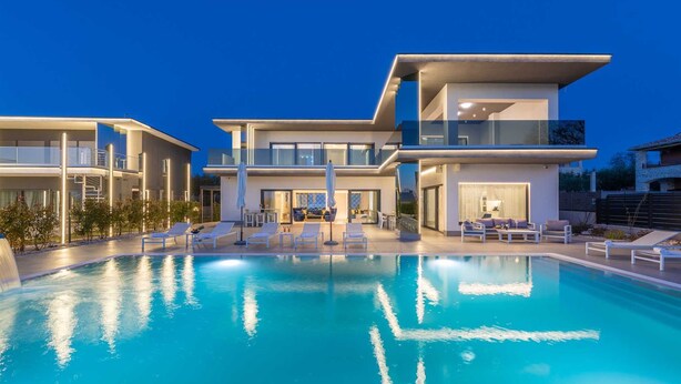 Ein modernes, zweistöckiges Haus mit Swimmingpool, Außenbereich und großem Glasbalkon.