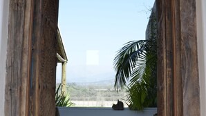 An open doorway leading to a balcony with a view of the landscape.