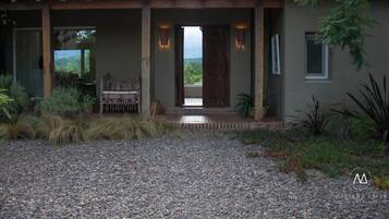 A building with a covered entrance, a gravel driveway, and a view of greenery in the background.
