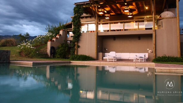 A modern building with a pool, outdoor seating, and a view of the surrounding landscape.