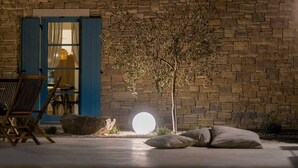 A stone wall with a tree, a blue door, and a round light source.