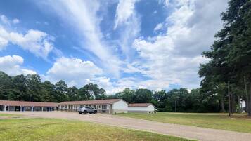 A motel with a gravel driveway, a parking area, and a grassy field.