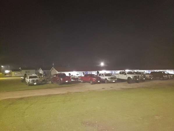 A parking lot at night with several vehicles parked.