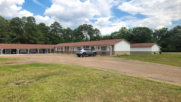 Un motel con varias habitaciones, un estacionamiento de grava y un campo cubierto de césped.