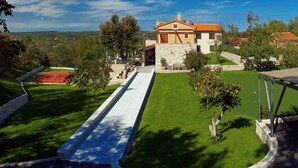 A house with a tennis court, a well-maintained lawn, and a stone pathway leading to the entrance. - Luxury Villa Retreat with Infinity Pool (Labin)