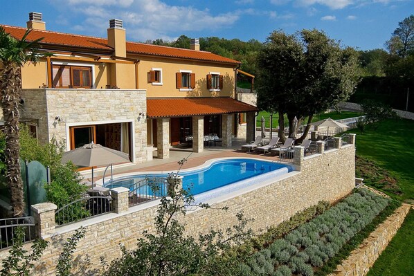 A two-story house with a swimming pool, stone walls, and a garden. - Luxury Villa Retreat with Infinity Pool (Labin)