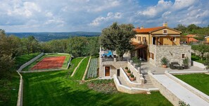 A luxurious villa with a tennis court, stone exterior, and a scenic view. - Luxury Villa Retreat with Infinity Pool (Labin)