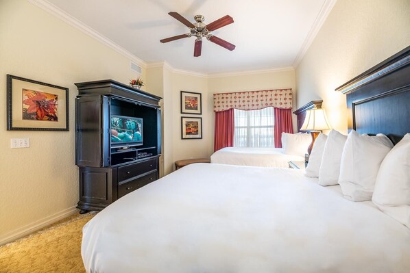A hotel room with a large bed, a television, a ceiling fan, and artwork on the walls. - 3BR Reunion Condo with Golf Course Views (Kissimmee)