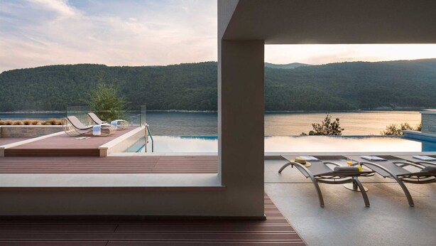 A balcony with a view of a lake and forested hills.