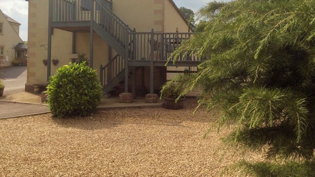 Ein Gebäude mit einer Treppe, die zu einem Balkon führt, umgeben von Kies und Blumentöpfen.