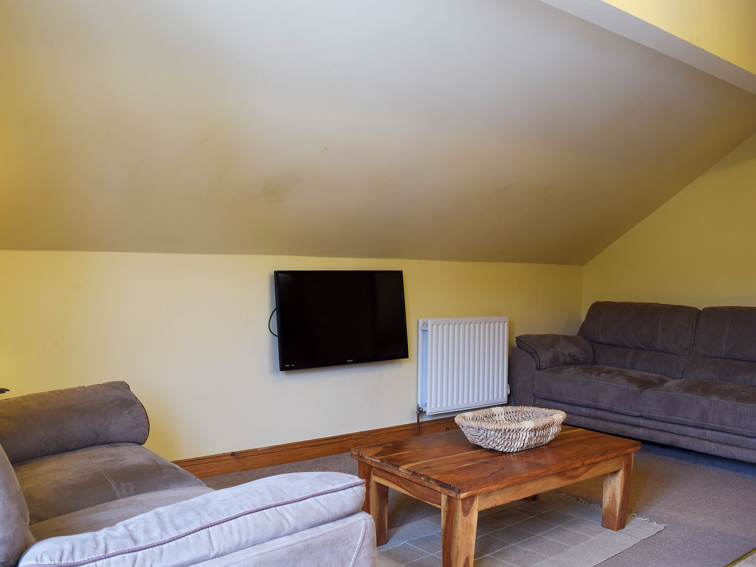 A living room with a sofa, a wooden coffee table, a television, and a radiator.