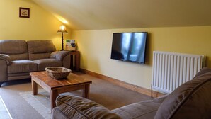 Ein Wohnzimmer mit einer Couch, einem Holztisch, einem Fernseher und einer Heizung.