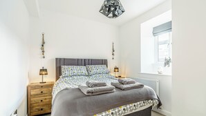 A bedroom with a bed, bedside tables, a hanging light fixture, a window with a view, and a radiator. - 2 bedroom accommodation in Alnwick (Alnwick)