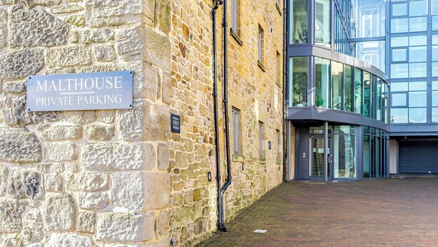 A stone building with a sign indicating private parking. - 2 bedroom accommodation in Alnwick (Alnwick)