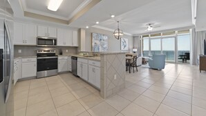 A modern kitchen with white cabinets, stainless steel appliances, and a large island. - Phoenix Orange Beach II 704 by Liquid Life (Orange Beach)
