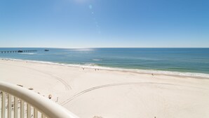 A beach with a pier extending into the water, a clear sky, and a calm sea. - Royal Palms 1002 by Liquid Life (Gulf Shores)
