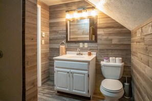 A bathroom with a wooden wall design, a white vanity, and a toilet.