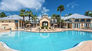 A large swimming pool with lounge chairs and palm trees, surrounded by buildings with a Mediterranean architectural style. - Beach Haven Private Heated Dip Pool! (Palm Coast)